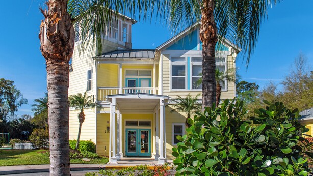 A two-story house with a porch, surrounded by palm trees and greenery. - Barefoot'n Resort Kissimmee Orlando (Kissimmee)