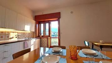 A kitchen with a dining table set for four, a window with a view, and white cabinets.