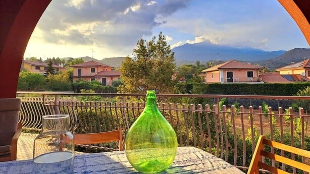 Un balcone con un tavolo, una bottiglia verde e un bicchiere.