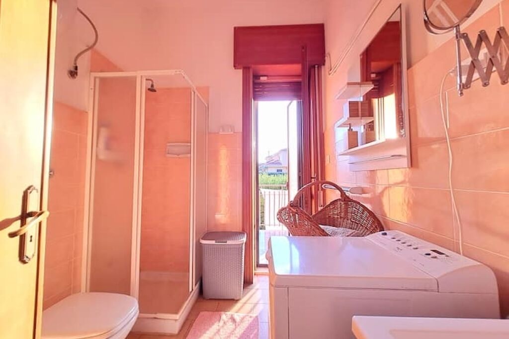 Une petite salle de bain comprenant une douche, des toilettes et un lave-linge.