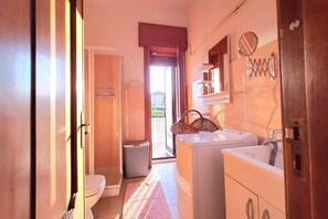A compact bathroom with a toilet, washing machine, and sink. - The Little Vineyard (Trecastagni)