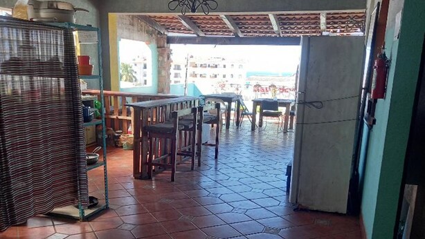 A spacious kitchen with a tiled floor, wooden ceiling beams, and a dining area with chairs and tables. - Hostal Luna Vallarta (Puerto Vallarta)
