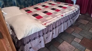 A bed with a quilt, a fan, and a red curtain. - Hostal Luna Vallarta (Puerto Vallarta)