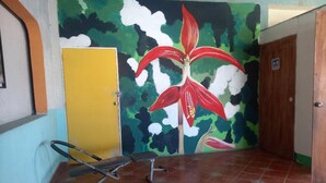 A room with a yellow door, a mural of a red flower, and a bench. - Hostal Luna Vallarta (Puerto Vallarta)