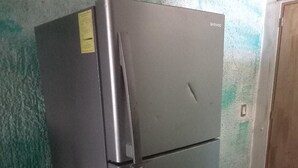A stainless steel refrigerator in a room with green walls and a wooden door. - Hostal Luna Vallarta (Puerto Vallarta)