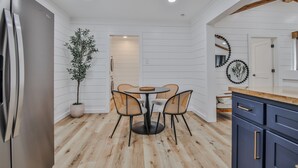 Een moderne keuken met een ronde eettafel, vier stoelen, een potplant en houten vloeren.