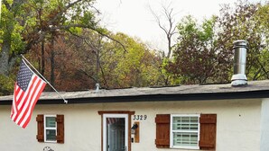 Une maison de plain-pied, avec le numéro 3329 sur la porte, une cheminée et un drapeau américain.