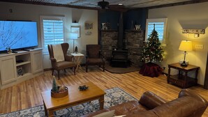 Un salon chaleureux avec une cheminée, un téléviseur et un sapin de Noël.