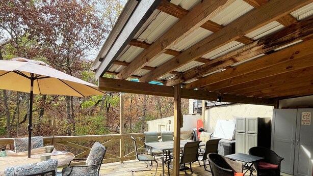 Une terrasse extérieure avec une plateforme en bois, du mobilier d’extérieur et un espace barbecue.