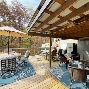 Une terrasse extérieure avec une plateforme en bois, du mobilier d’extérieur et un espace barbecue.