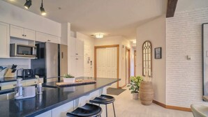 A modern kitchen with a central island, bar stools, and a white brick accent wall.