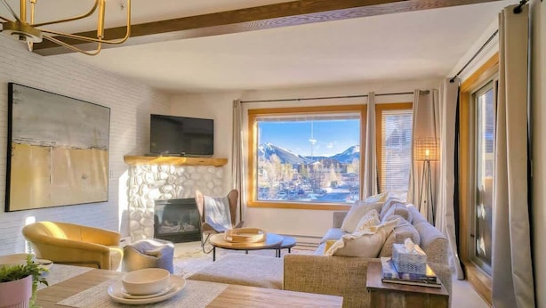 A cozy living room with a fireplace, a sofa, and a dining area with a table set for two.