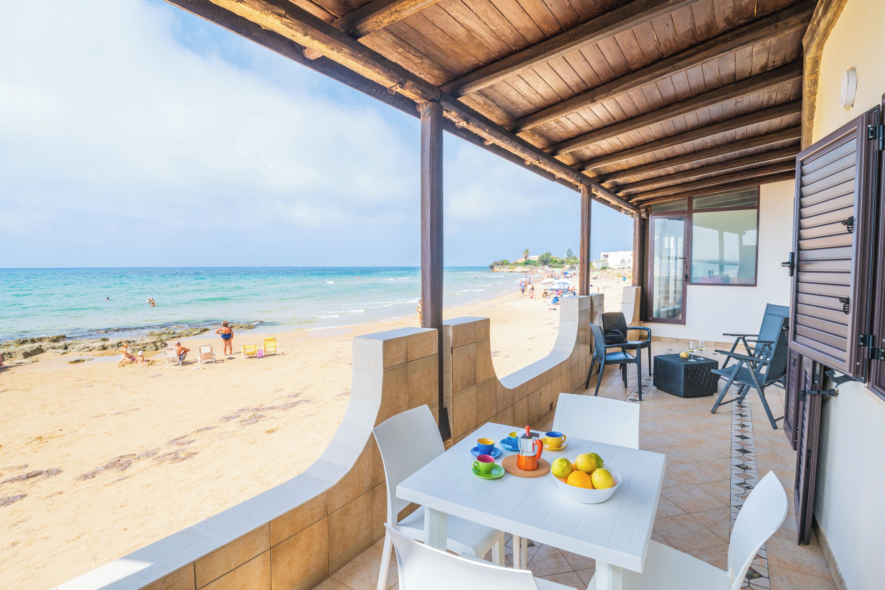 A covered outdoor seating area with a view of the beach and ocean.