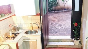 A kitchen with a sink, stove, and a potted plant. - La Piccina (Catania)