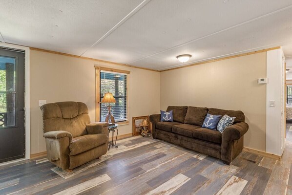 A living room with a brown sofa, a brown armchair, and a lamp. - The Rustic Minnow: Walk to Lake, Enjoy Outdoor Amenities and Stunning Landscape (Hulbert)