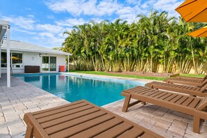 Une piscine avec des chaises longues et un bâtiment doté d’un patio couvert.