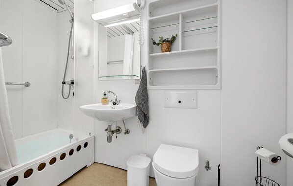 Un bagno moderno con vasca, lavandino, WC e uno specchio con ripiani.