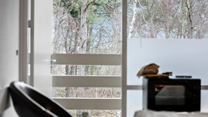 Ein Zimmer mit großem Fenster, einem Stuhl und einem kleinen Tisch mit einer Tasche darauf.