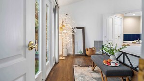 A hallway with a bench, a potted plant, and a mirror.