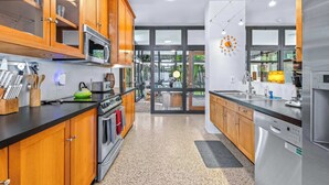 A modern kitchen with wooden cabinets, stainless steel appliances, and a view of a balcony.
