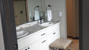 A bathroom with two sinks, a large mirror, and a bench. - 4-bedroom house in charming Coeur d'Alene with AC, WiFi, fitness room (Coeur d'Alene)