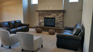 A living room with a stone fireplace, leather sofas, and a television. - 4-bedroom house in charming Coeur d'Alene with AC, WiFi, fitness room (Coeur d'Alene)