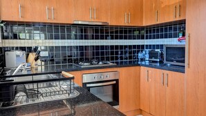 Et moderne køkken med træskabe, en backsplash med sorte fliser, stålstål-hvidevarer og en bordplade i granit.