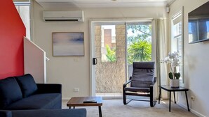 En moderne stue med sofa, stol, lille bord og en potteplante.