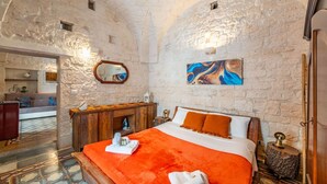 A room with a bed, a wooden dresser, a mirror, and a painting on the wall. - Antica Casa 1600 by Rentbeat (Ostuni)