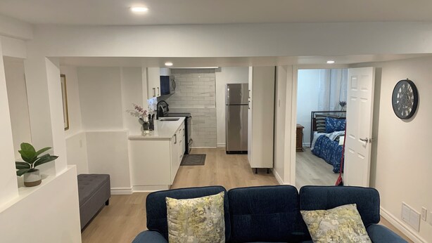 A modern living room with a dark blue sofa and a kitchen in the background.