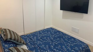 A bedroom with a bed, a TV mounted on the wall, and a closet.