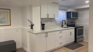 A modern kitchen with white cabinetry, a black faucet, a microwave, and an oven.