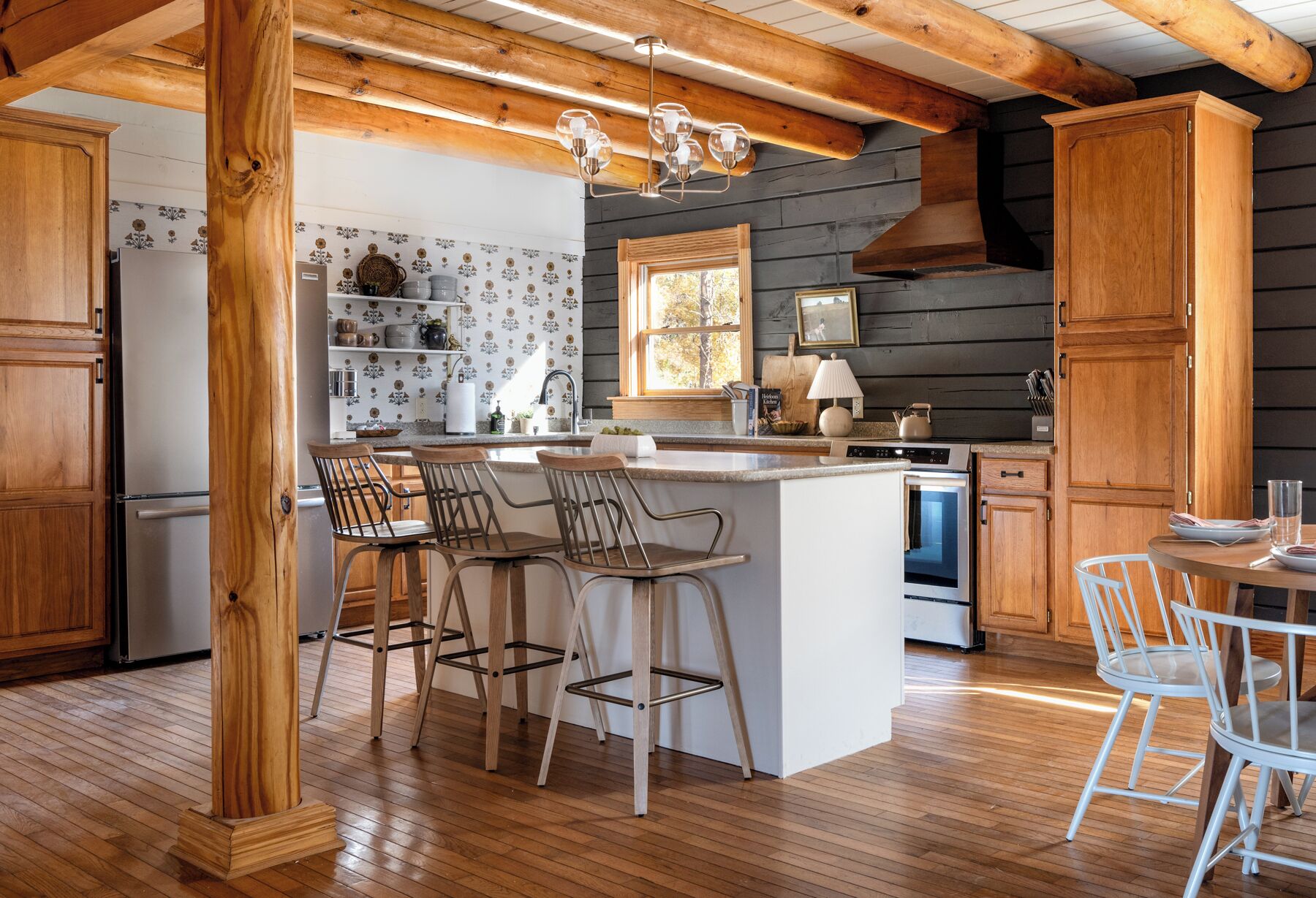 A modern kitchen with wooden accents, a central island, bar stools, and a dining area.