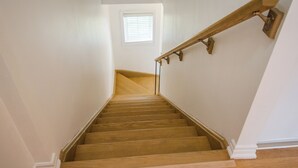 A wooden staircase with a handrail and a window at the top.