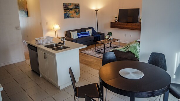A modern apartment with a kitchen, dining area, and living room. It includes a sofa, a coffee table, and a TV.
