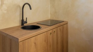 Una cocina con encimera de madera, un lavamanos negro y un solo armario.