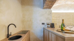 Una cocina moderna con encimera de madera, un lavamanos negro y techo de ladrillo.