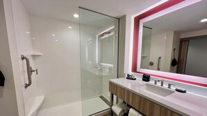 A modern bathroom with a glass shower enclosure, a vanity with a mirror, and a towel rack.