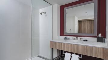 A modern bathroom with a glass shower enclosure, a wooden vanity with a mirror, and a towel rack.