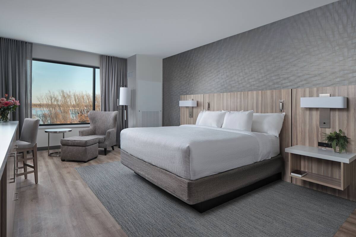 Un hotel moderno con una cama grande, un escritorio, una silla y vistas al exterior.