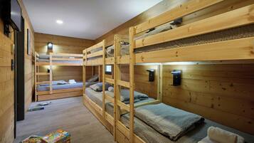 Une chambre avec des lits superposés, des murs en bois, un luminaire au plafond et une petite fenêtre.