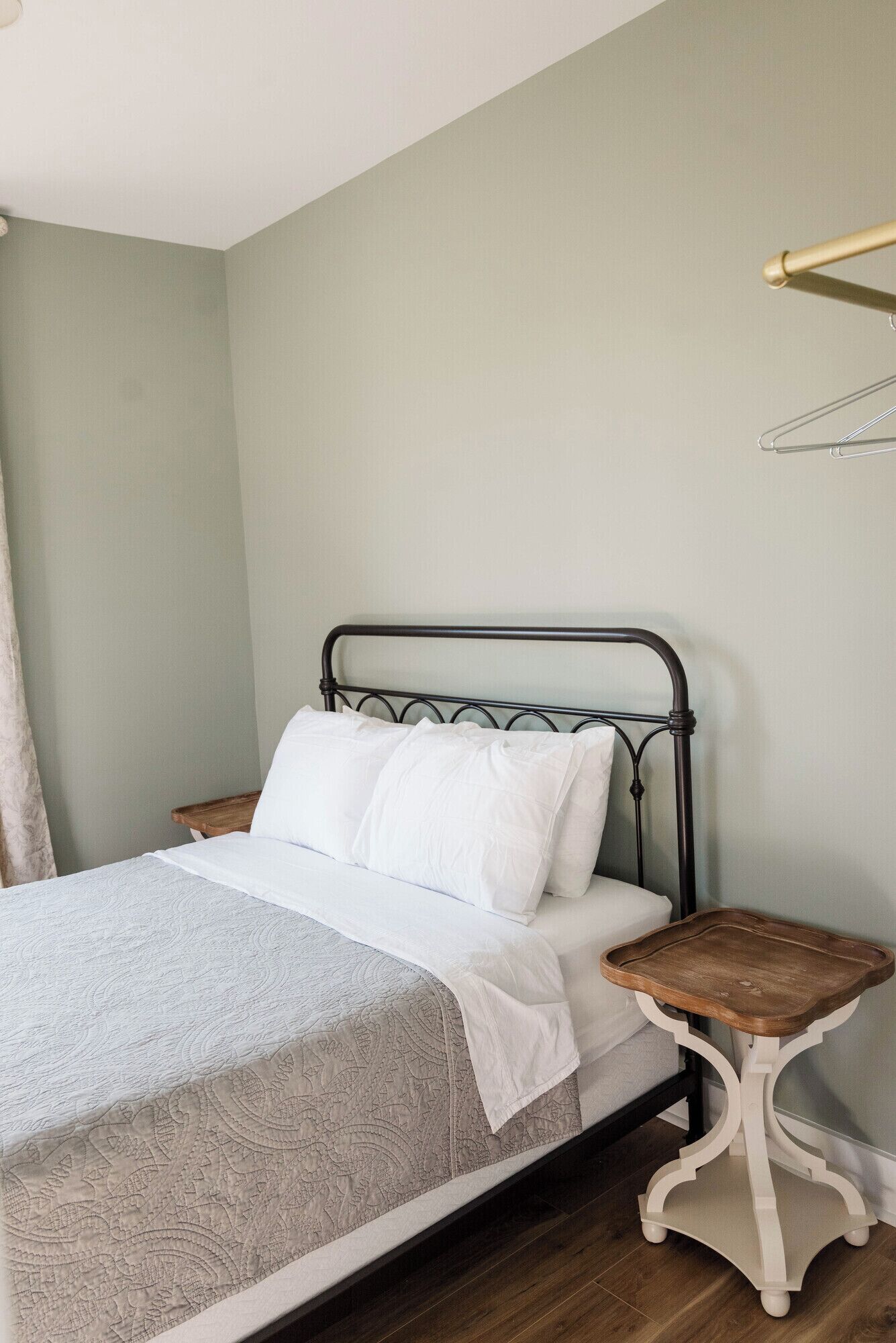 A bed with a metal frame, white bedding, and a wooden bedside table.