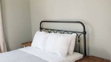 A bed with a metal frame, white bedding, and a wooden bedside table.
