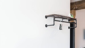 A minimalist room with a wooden table, a chair, and a wall-mounted rack. - The Victorian Room @ Main Street Lofts (Victoria)