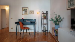 A modern living room with a blue desk, a red chair, a potted plant, and a bookshelf. - Ricasoli 37 - Flo Apartments (Firenze)