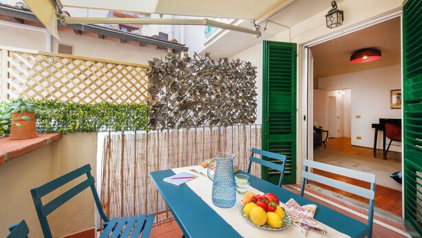 A dining area with a table set for two, a basket of fruit, and a pitcher of water. - Ricasoli 37 - Flo Apartments (Firenze)