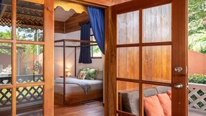 Ein Holzinnenraum mit einer großen Schiebetür, die zu einem Schlafzimmer mit Bett und Blick ins Grüne führt.