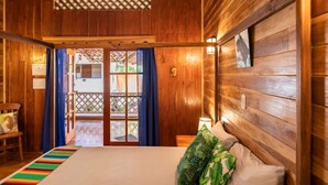 Una habitación de madera con una cama, una silla y vistas al exterior a través de un ventanal.