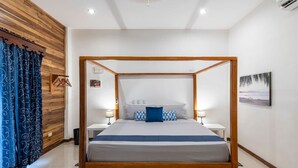 Uma cama com dossel de madeira, roupa de cama branca e duas mesas de cabeceira com abajures.