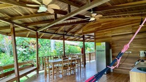 A wooden deck with a hammock, outdoor dining area, and a kitchen area. - Tropical Vibe Home | Pool | Walk to Beach & Dining (Manzanillo)